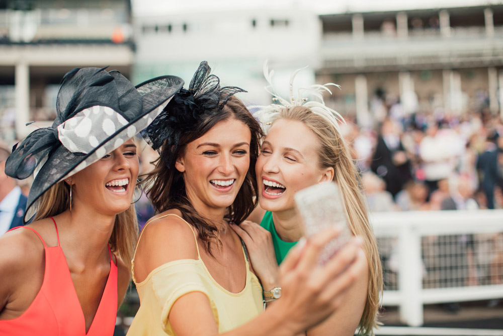three ladies wearing fascinators taking selfie at the spring racing carnival